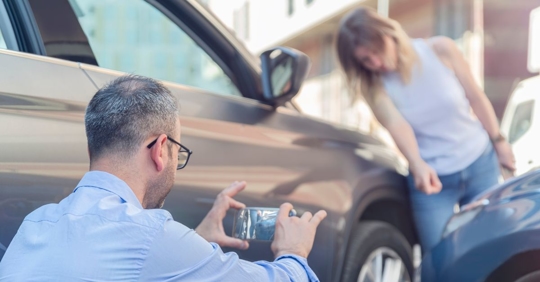 Man taking photo of car accident with woman